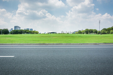 Wall Mural - Empty asphalt road and green lawn under blue sky