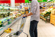© kalinichenkod - sale, shopping, consumerism and people concept - man with shopping cart at grocery store or supermarket