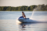 Fototapeta Dmuchawce - Young amateur girl rides a hydrocycle on the lake. Water sports concept.