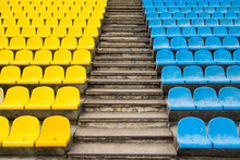 Empty Bright Yellow And Blue Seats For Fans At The Football Stadium In The Summer Between The Stairs