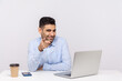 © khosrork - Glad smiling businessman sitting office workplace with laptop on desk, pointing finger to camera, looking pleased happy, choosing lucky coworker. indoor studio shot isolated on white background