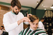 © sealovers - handsome barber cutting the hair of a young brunette in the barber shop