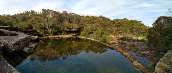 Beautiful panoramic view of Wattamolla dam with reflections of trees and blue cloudy sky, Wattamolla creek, Royal National Park, New South Wales, Australia