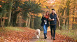 © Monkey Business - Loving Couple Walking With Pet Golden Retriever Dog Along Autumn Woodland Path Through Trees