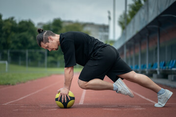 Wall Mural - muscular young athlete has workout and exercising with medicine ball outdoor