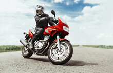 A Man Rides A Motorcycle On The Highway To The Camera. A Man On A Red Motorcycle Makes A Turn In Front Of The Camera
