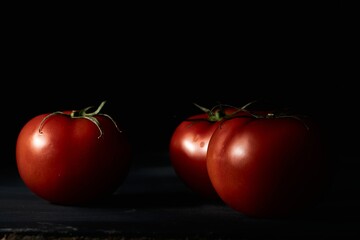 Canvas Print - Closeup shot of three fresh tomatoes on a black background