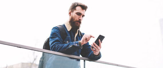 bearded male typing text message for send to friend via application on modern telephone gadget, cauc