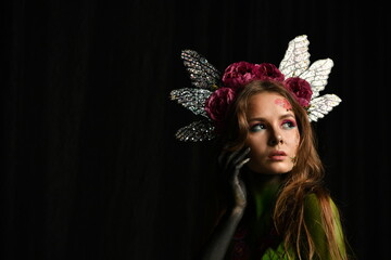 beautiful girl painted with green paint and flowers on her face and burgundy peonies in her body posing in different poses