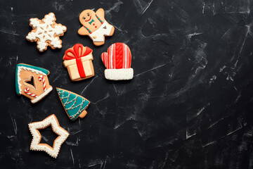 Wall Mural - A variety of multi-colored Christmas gingerbread cookies on a black stone background, flat lay. View from above, space for text.