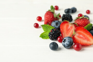 Mix of fresh berries on wooden background, space for text