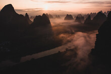 Silhouettes Of Big Tall Mountains Against Bright Cloudy Sky On Foggy Morning In Guilim