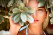 Leinwandbild Motiv Portrait of a blonde with natural beauty among the leaves of tropical trees. Spa and pleasure
