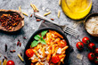 © Luis Mario Hernandez/ADDICTIVE STOCK - Top view of delicious pasta decorated with ripe cherry tomatoes and fresh basil near wooden bowl with arrabiata sauce and grated Parmesan cheese