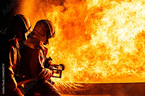 Fotografía Firefighters use twirl water fog spraying down fire flame.