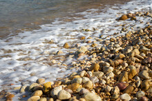 Stones Being Washed By An Incoming Tide At Ramla Bay, Gozo, Malta.