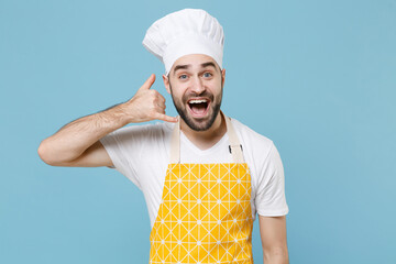 Wall Mural - Excited young bearded male chef or cook baker man in apron white t-shirt toque chefs hat isolated on blue background. Cooking food concept. Mock up copy space. Doing phone gesture says call me back.