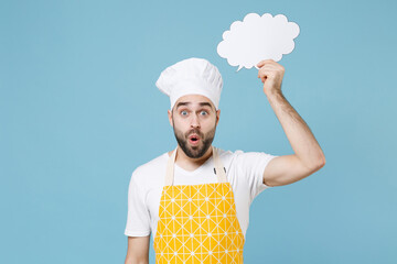 Wall Mural - Shocked young bearded male chef or cook baker man in apron white t-shirt toque chefs hat isolated on blue background. Cooking food concept. Mock up copy space Hold empty blank Say cloud speech bubble.