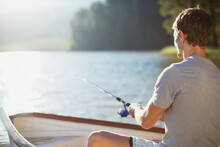Man Fishing In Rowboat On Calm Lake