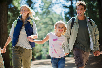 Wall Mural - Smiling family holding hands and running in woods