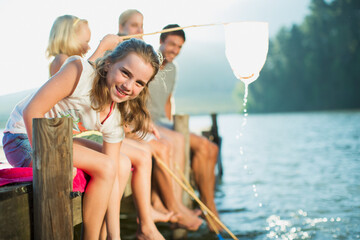 Smiling family with fishing nets on dock over lake