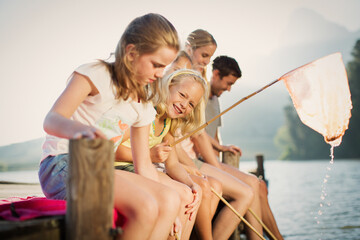 Wall Mural - Family with fishing nets on dock over lake