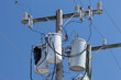 Partially scorched powerline transformers against blue sky