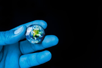 close up blue color hand is holding the earth planet on a black background