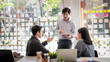 © amnaj - Group of young asian modern people in smart casual wear having a brainstorm meeting. Group of young asian business people discussing in the meeting.