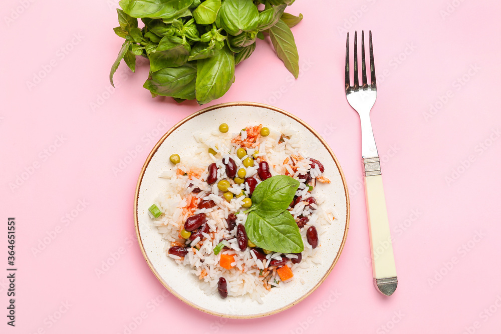 Plate with tasty rice, beans and vegetables on color background