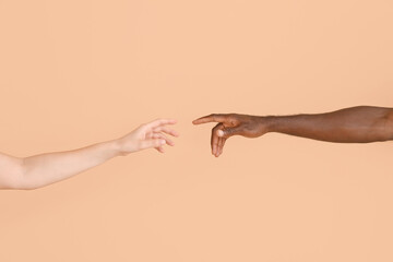 Wall Mural - Hands of Caucasian woman and African-American man reaching out to each other on color background. Racism concept