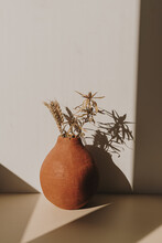 Red Handmade Clay Flower Pot With Dry Wheat / Rye Bouquet In Sunlight Shadows On White Background. Minimal Modern Interior Decoration Concept.