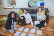 © zinkevych - Successful two girls and guy sitting on floor with documents.