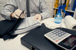 © soleg - concept of cleaning or disinfecting the office desk - a businessman cleans the workplace, computer keyboard, document folders, uses a spray gun sanitizer, gloves and paper napkins.