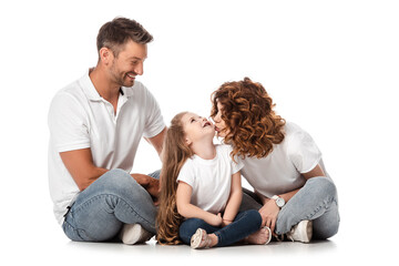 cheerful man looking at wife kissing daughter on white