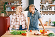 © GVS - Smiling young couple cooking together in the kitchen at home