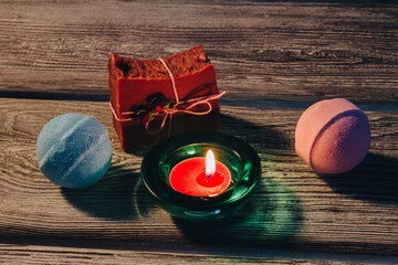 Wall Mural - Spa concept with bath bombs, handmade soap and burning candle onwooden background. Blue, strawberry bath bombs.