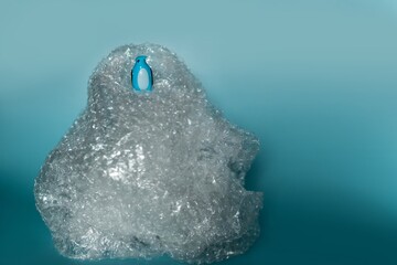 Poster - Closeup shot of a blue penguin toy on a plastic bag with a blue background