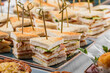 Mini sandwich appetizer with cheese and prosciutto in plate on banquet table. Catering food, canape and snacks