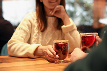 Canvas Print - Lovely couple with tasty mulled wine at table in cafe, closeup