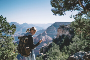 smiling female tourist with backpack satisfied with having roaming mobile connection for communicati