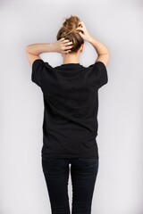 Wall Mural - Young female wearing black short sleeve t-shirt standing against a white wall