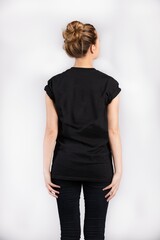 Wall Mural - Young female wearing black short sleeve t-shirt standing against a white wall