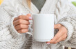 © woodpencil - White ceramic mug mockup. Woman in Sweater Holding a Warm Cup of Coffee. Copy space for your print