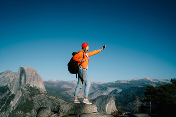 Wall Mural - young female travel blogger taking selfie on smartphone camera during hiking tour in mountain,girl w