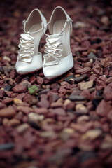 A pair of white elegant bride shoes on a rocks background