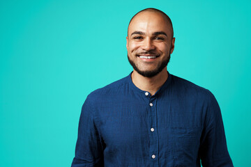 Portrait of a dark-skinned cheerful smiling man against turquoise background