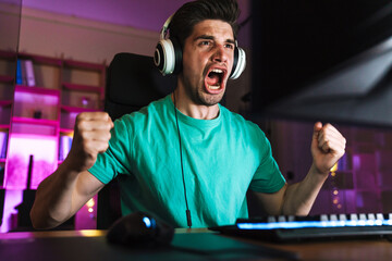 Wall Mural - Image of excited man making winner gesture while playing video game