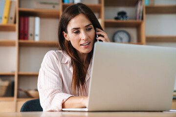 Wall Mural - Image of businesswoman talking on mobile phone while working with laptop