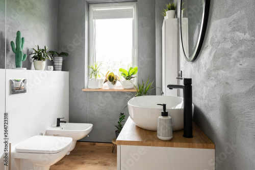 Fotomural Stylish interior of bathroom with grey wall, plants, window and wooden furniture in scandinavian style